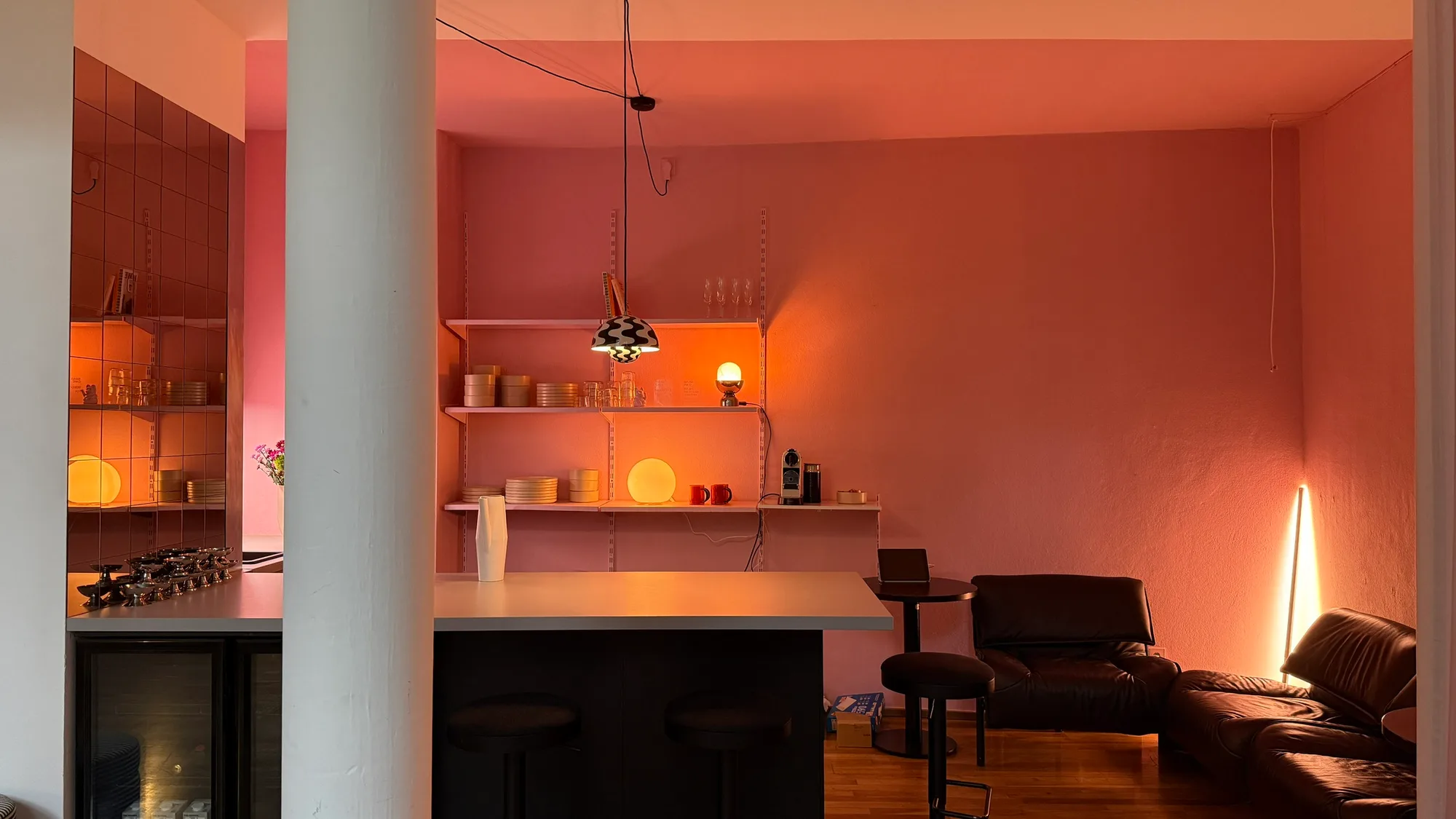 Küche des BAAD Studio mit rosa Wand, rosa Vorhang und orangem Hocker